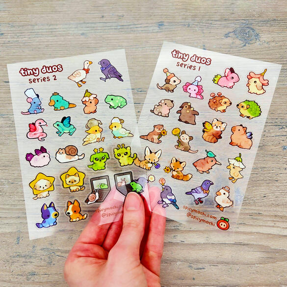Picture of a hand holding two separate sticker sheets featuring multiple sets of animal friends.